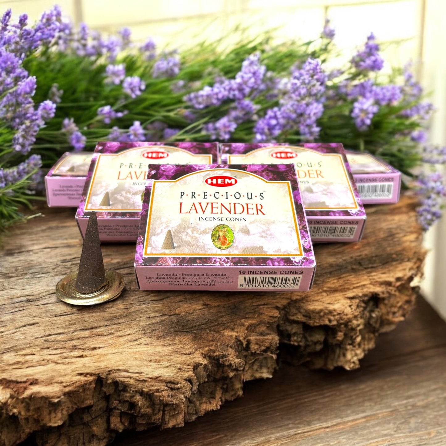 Neatos Elements Precious Lavender incense cones in purple boxes with lavender sprigs. One cone sits on a brass holder.