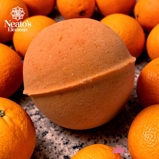 Neatos Elements orange bath bomb with blood orange fragrance, surrounded by fresh oranges.