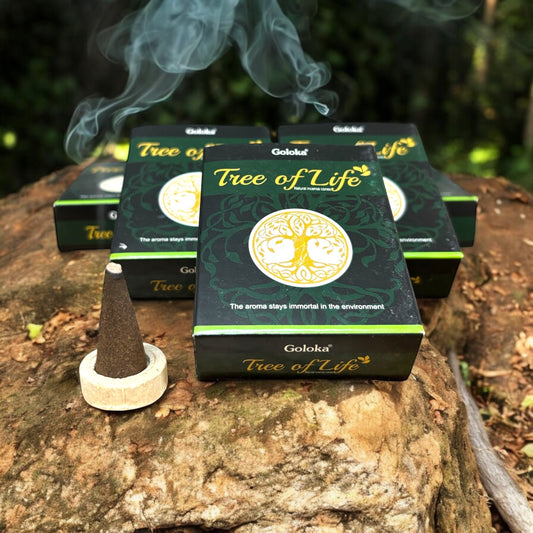 Neatos Elements Tree of Life incense cones in dark green packaging with a yellow tree symbol. One cone burns on a wooden stand.