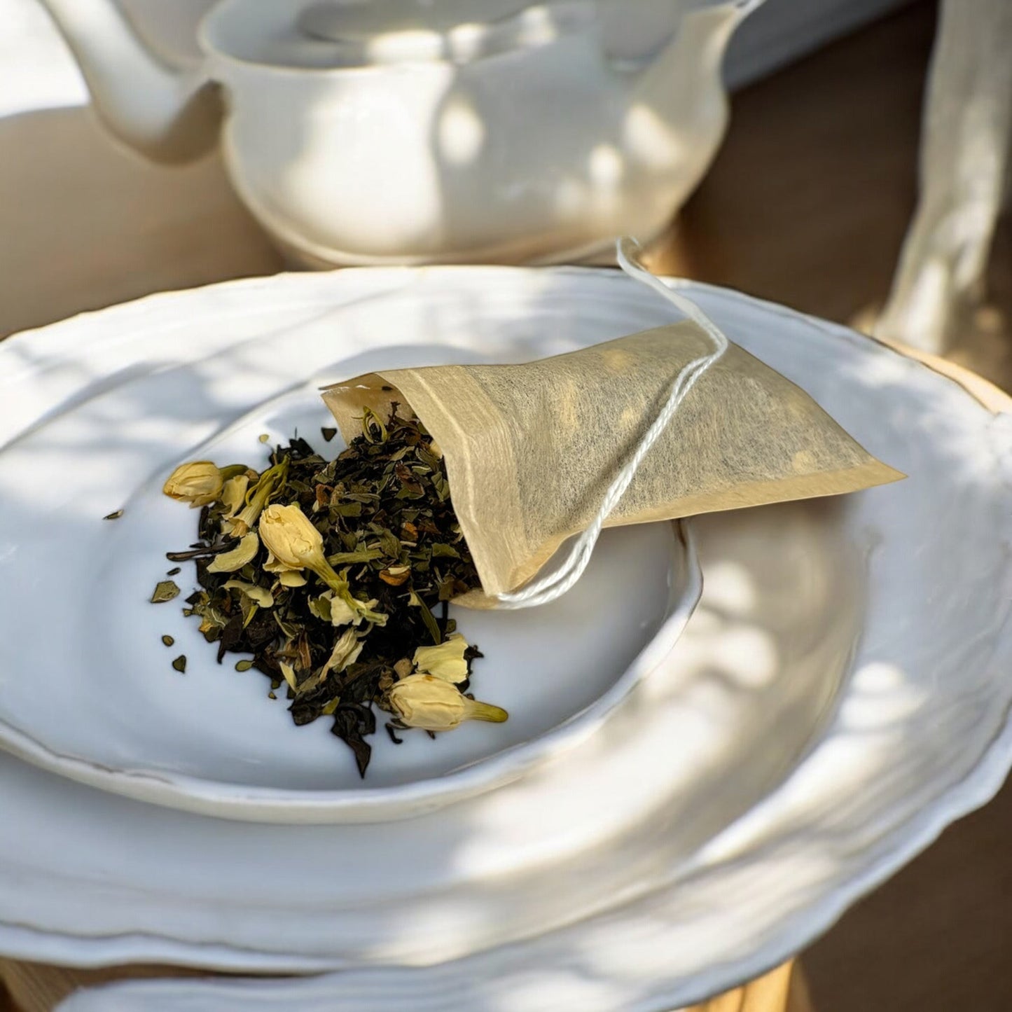 Neatos Elements Artic Blitz Tea Blend loose leaf tea with jasmine flowers and mint, in a paper sachet on a white plate.