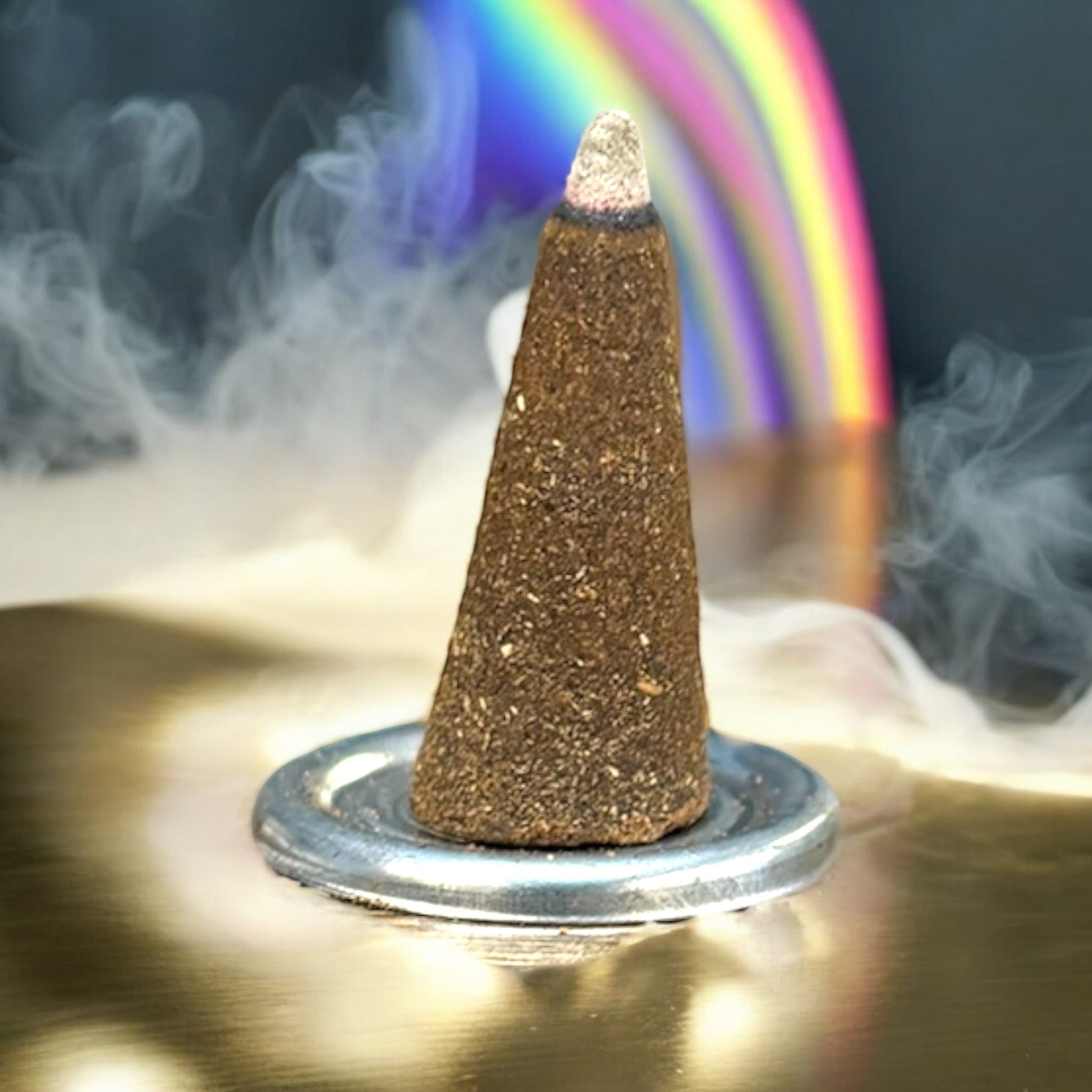 Neatos Elements Attracts Money incense cone burning with smoke, featuring a rainbow in the background.