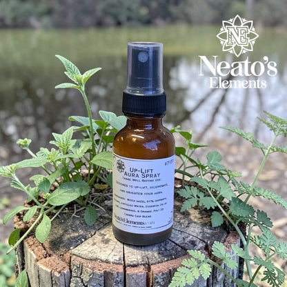 Neato's Elements Up-Lift Crystal Infused Aura Spray in amber bottle with spray top, surrounded by greenery.