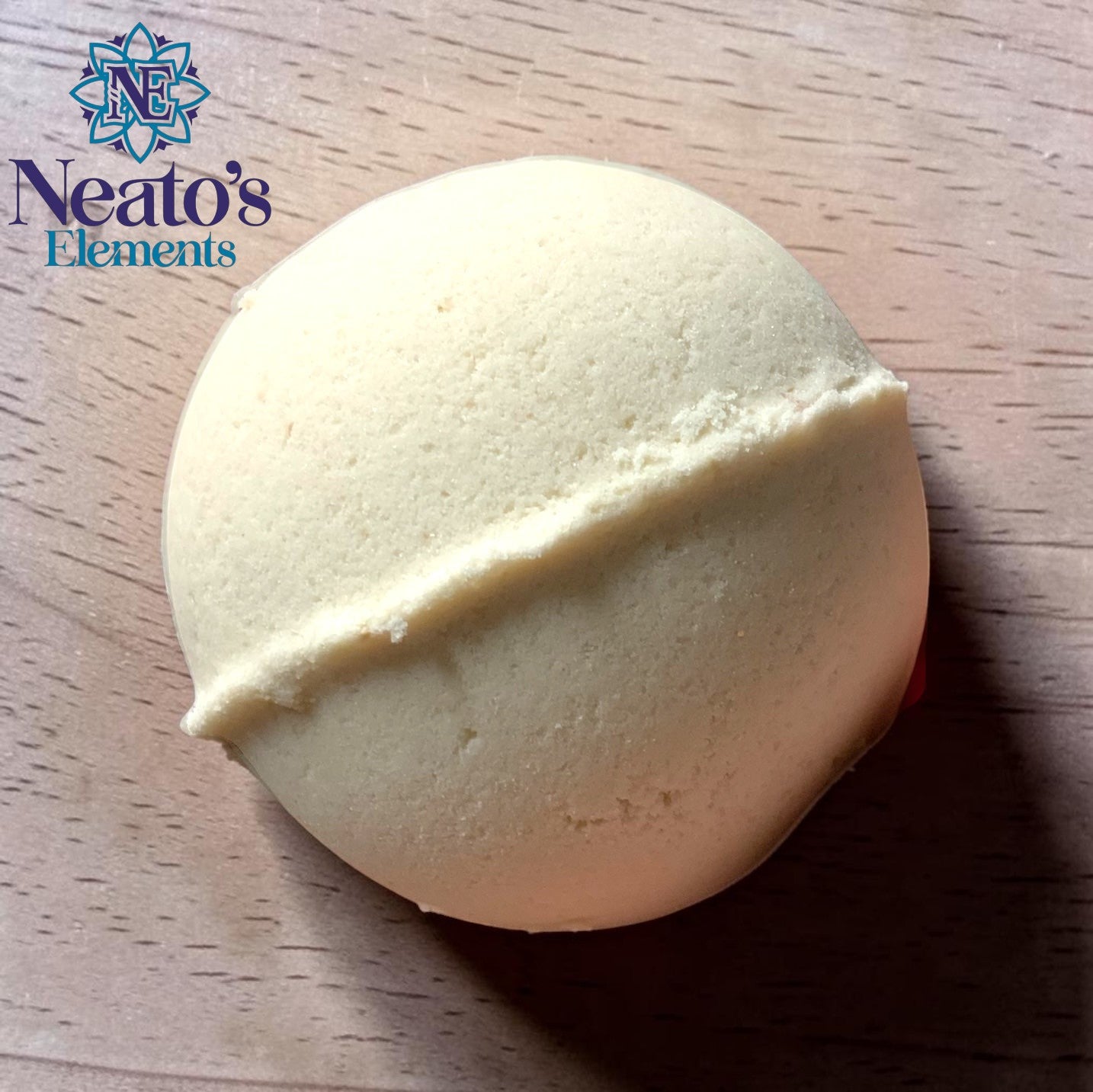 Neatos Elements I'm Coconut About You bath bomb, creamy white with a dividing line, surrounded by red roses on a pink background.