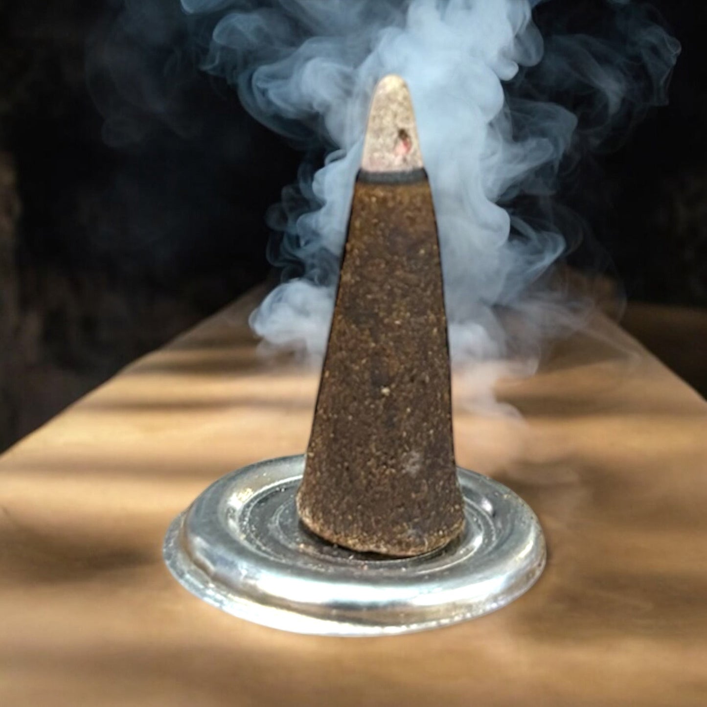 Neatos Elements Dragons Blood incense cone burning on a silver dish, releasing white smoke.