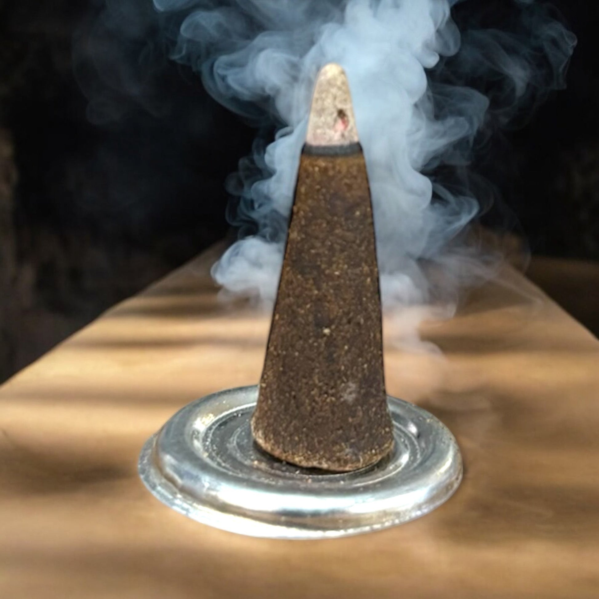 Neatos Elements Dragons Blood incense cone burning on a silver dish, releasing white smoke.