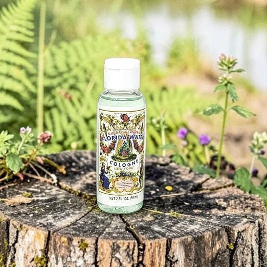 Neatos Elements Florida Water Cologne 2 oz bottle on a mossy tree stump with ferns and a pond in the background.