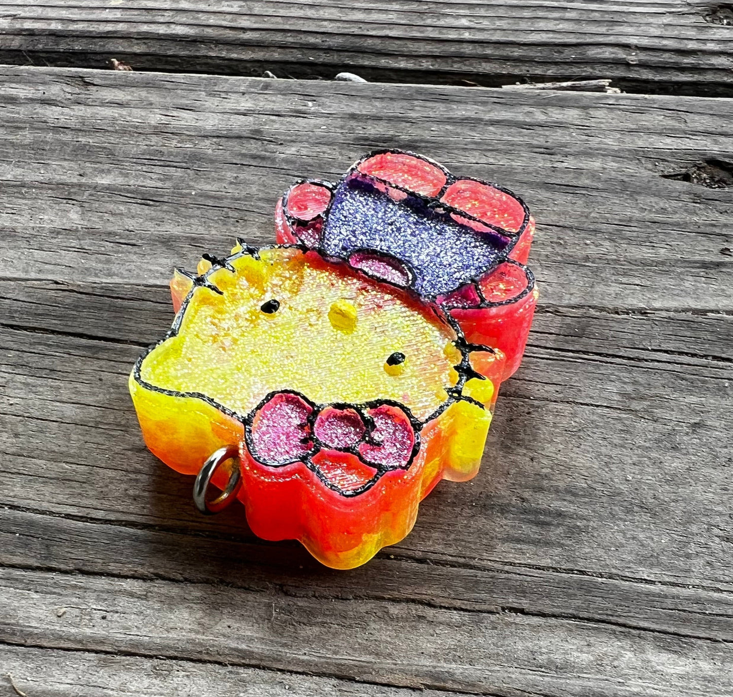 Neatos Elements Island Sunset Hello Kitty car freshie, yellow and orange with pink bow and purple bow accessory.