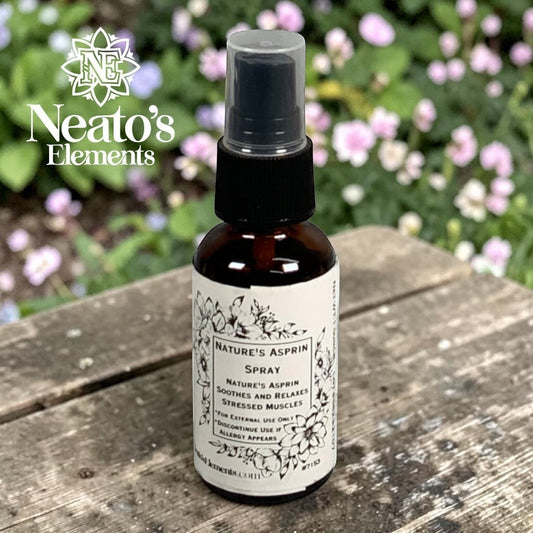Neato's Elements Nature's Asprin herbal spray in a brown glass bottle with a black spray top, on a wooden surface with flowers in the background.