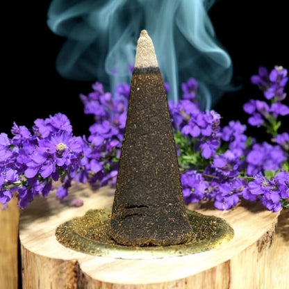 Neatos Elements Precious Lavender incense cone burning with blue smoke, surrounded by purple flowers on a wooden base.