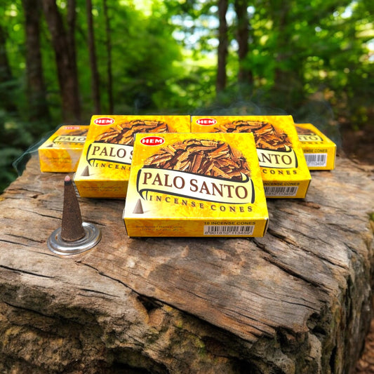 Neatos Elements Palo Santo Incense Cones in yellow packaging, one cone burning on a rustic wooden surface with a forest background.