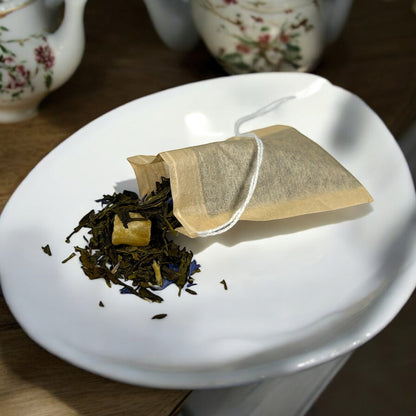 Neatos Elements Paradise Green Tea Blend loose leaf tea with pineapple pieces and blue cornflower petals spilling from a tea bag.