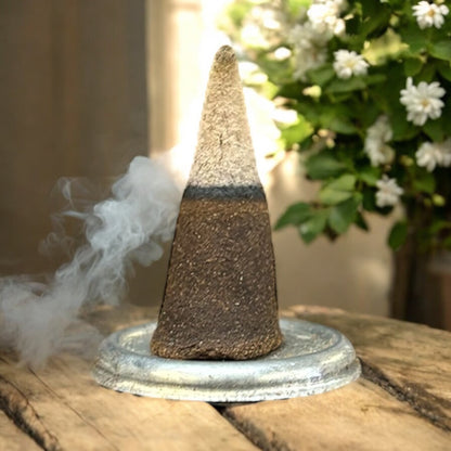 Neatos Elements Precious Jasmine incense cone burning, releasing white smoke, on a metal dish.
