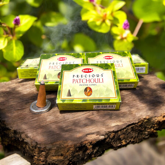 Neatos Elements Precious Patchouli incense cones, earthy scent, 10 cones per pack, burning on a wooden surface with smoke rising.