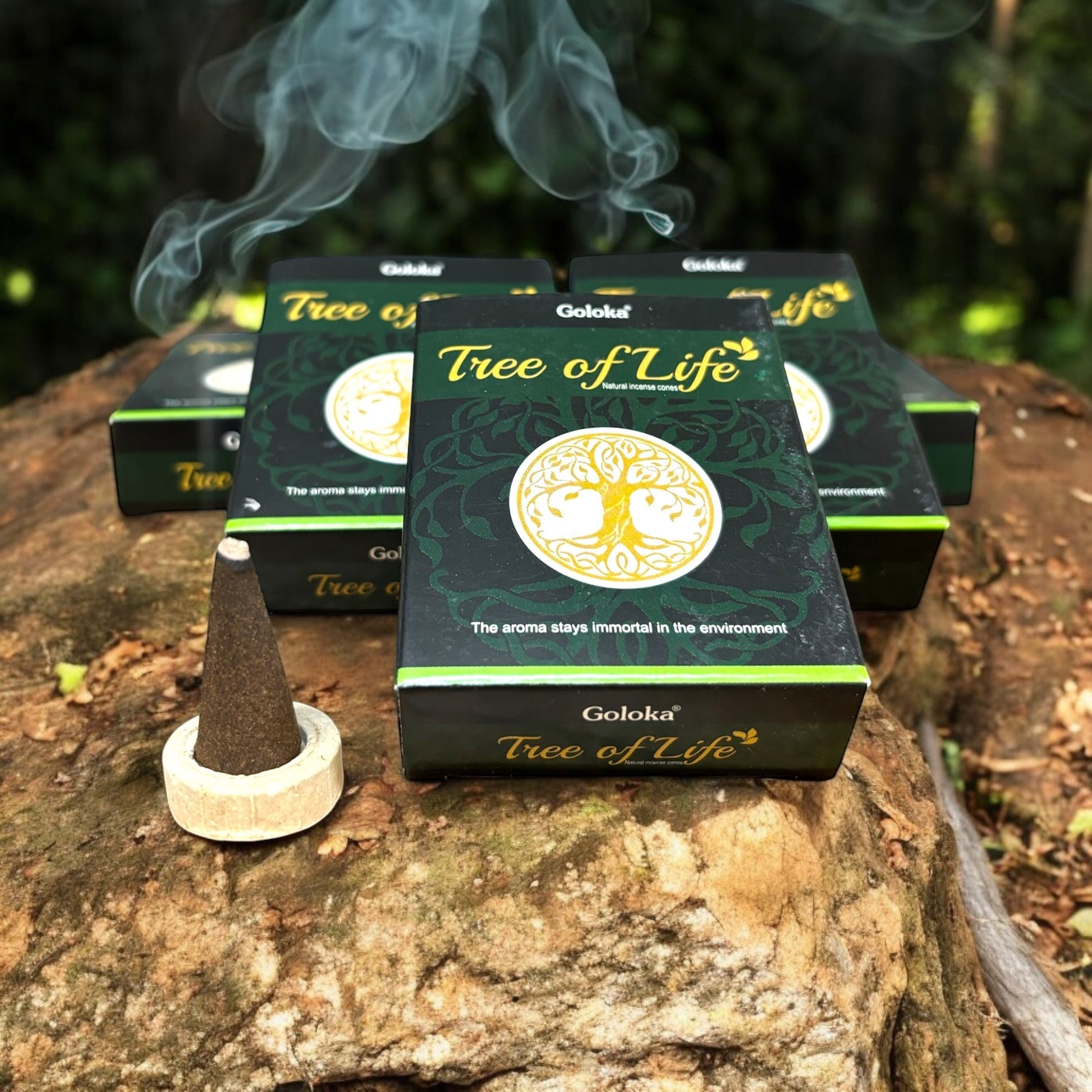 Neatos Elements Tree of Life incense cones in dark green packaging with a yellow tree symbol. One cone burns on a wooden stand.