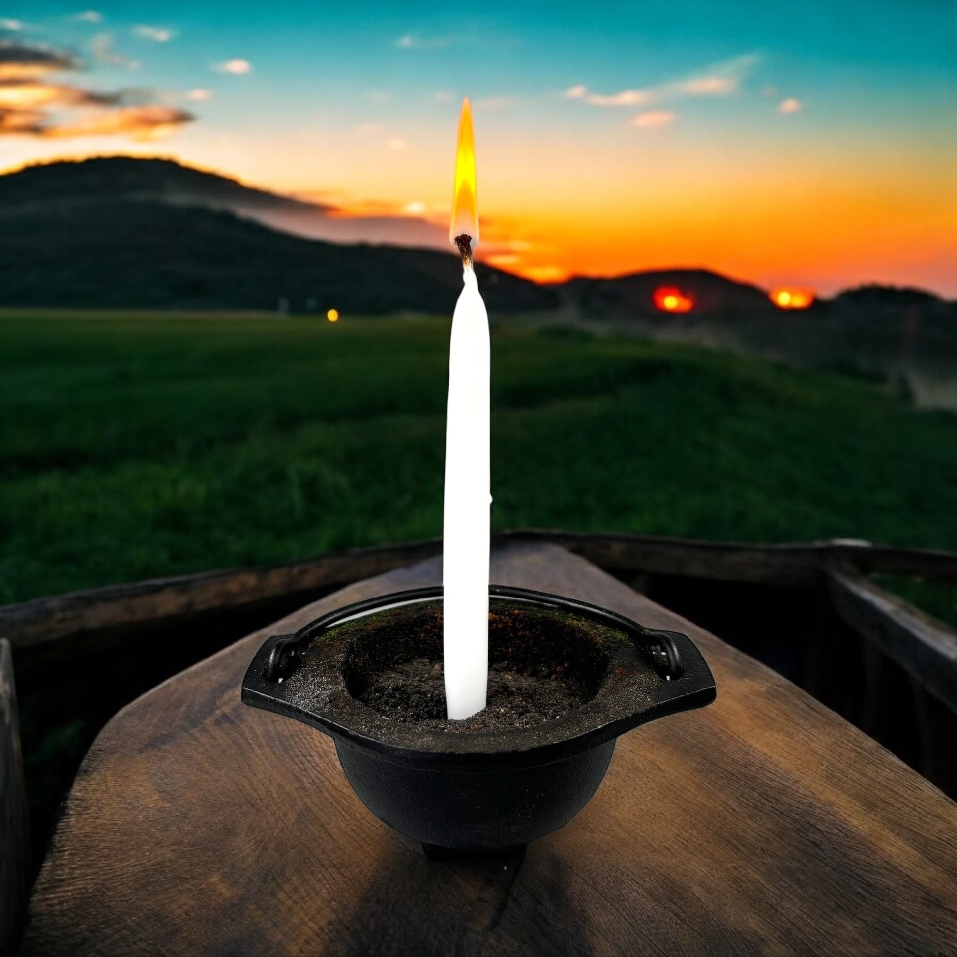 Neatos Elements hand-dipped white candle burning in a cauldron outdoors at sunset, used for divination and magic.