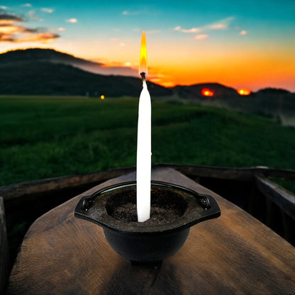 Neatos Elements hand-dipped white candle burning in a cauldron outdoors at sunset, used for divination and magic.