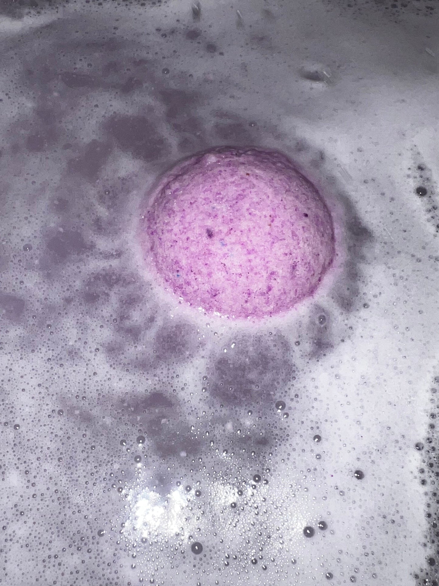Neatos Elements Goddess of the Night Bath Bomb fizzing in purple water with white foam.